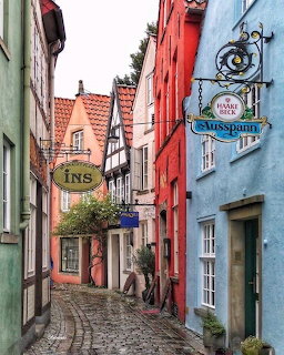 Narrow cobblestone street lined with colorful half-timbered buildings in a German village