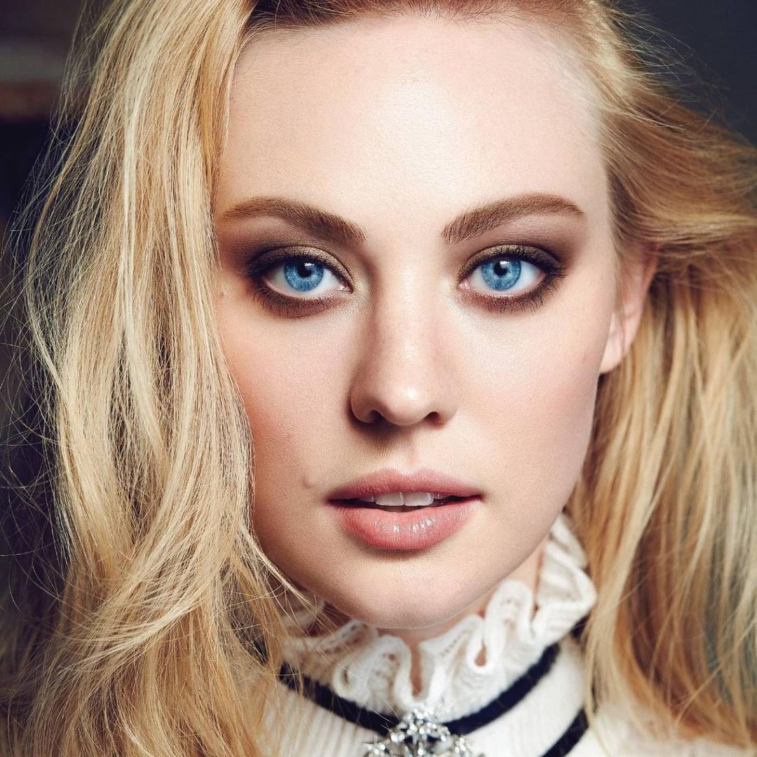 Portrait of blonde woman with blue eyes in white turtleneck and black choker