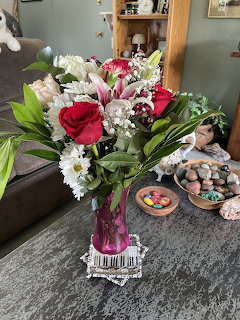 Bouquet of red roses, pink lilies, and white flowers in a pink vase on a coffee table