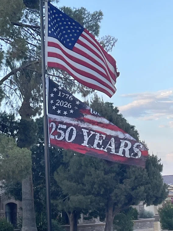 American flag flying above a red and white '250 Years 1776–2026' anniversary banner on a flagpole