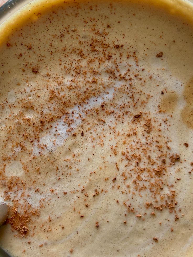 Overhead view of coffee drink with cinnamon sprinkled on foamy surface