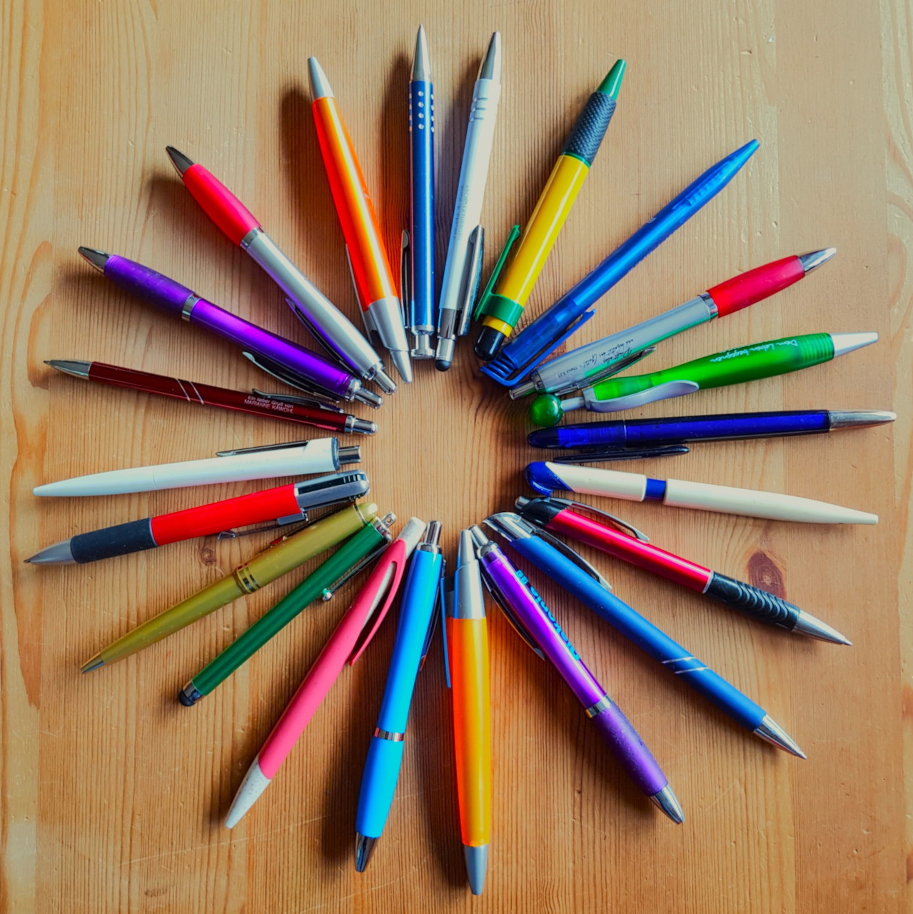 Colorful pens arranged in a circle on a wooden table