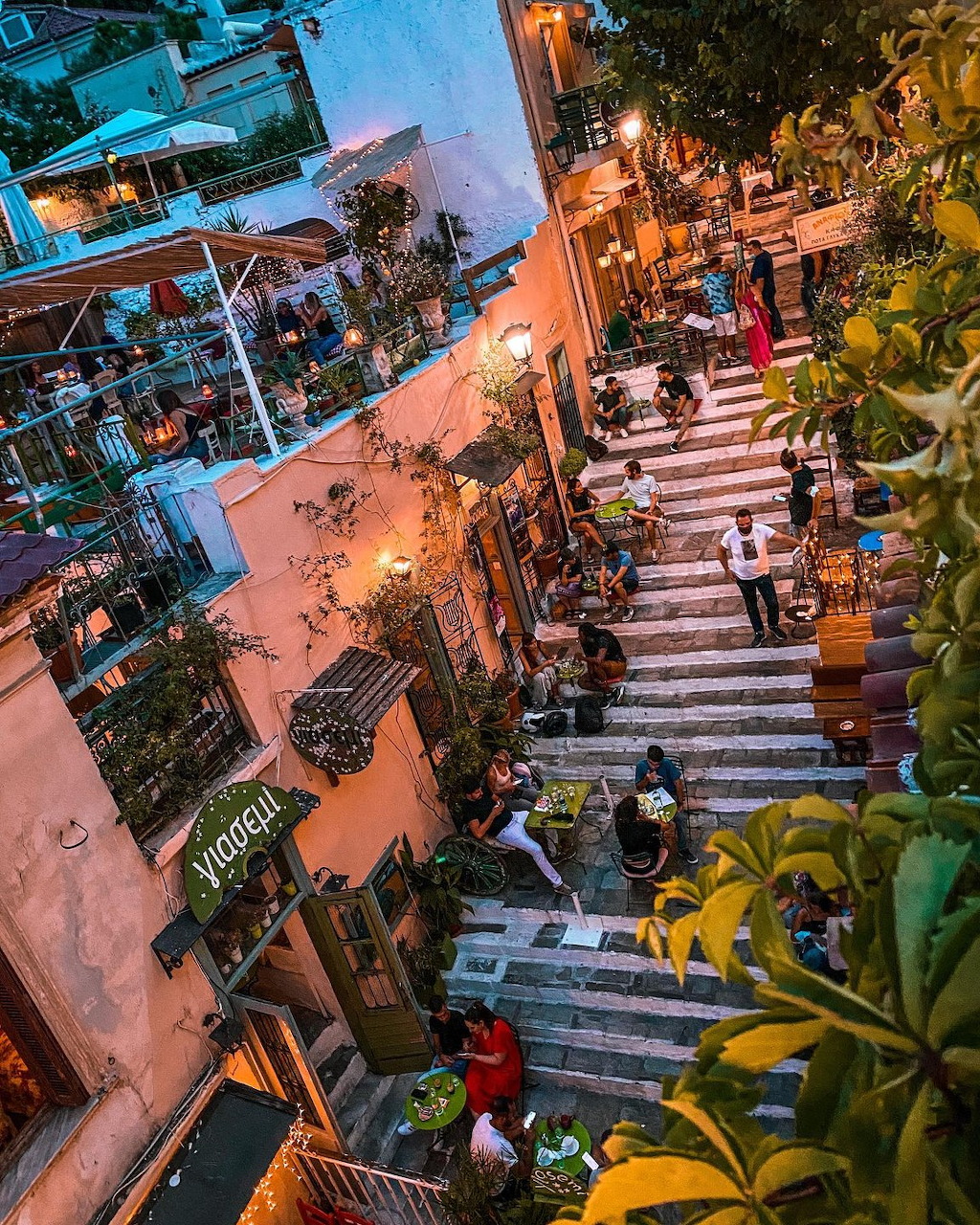 Overhead view of a lively pedestrian street in Plaka, Athens with cafes, stairs, and people dining outdoors at dusk