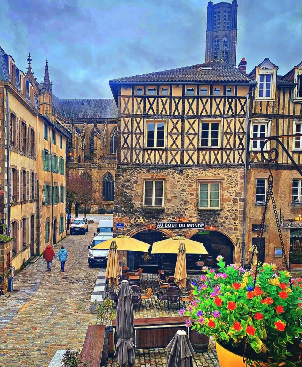 Medieval square in Limoges with half-timbered buildings, cathedral tower, café terraces and flower planters