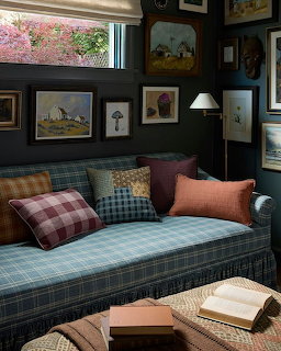 Cozy living room with plaid sofa, colorful cushions, framed artwork, and books on a coffee table