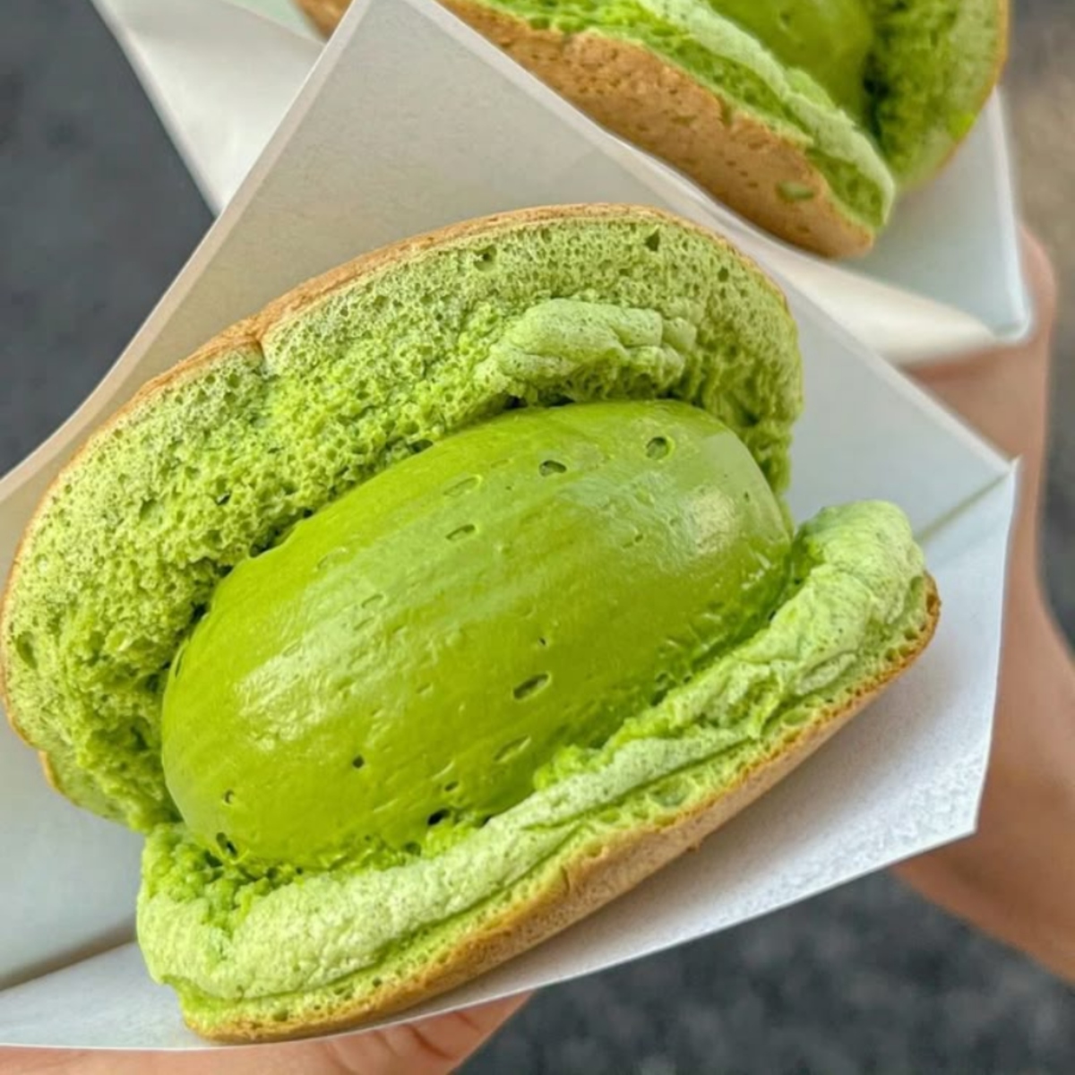Close-up of a green matcha pastry with creamy filling on a white tray