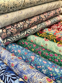 Close-up of stacked rolls of colorful patterned fabric with floral and botanical prints