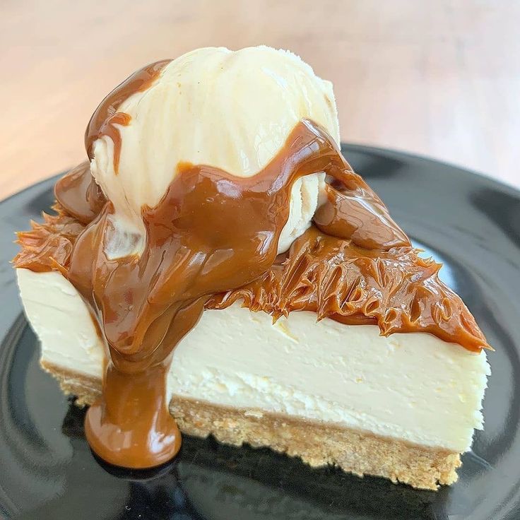 Slice of white cheesecake with caramel drizzle on a dark plate