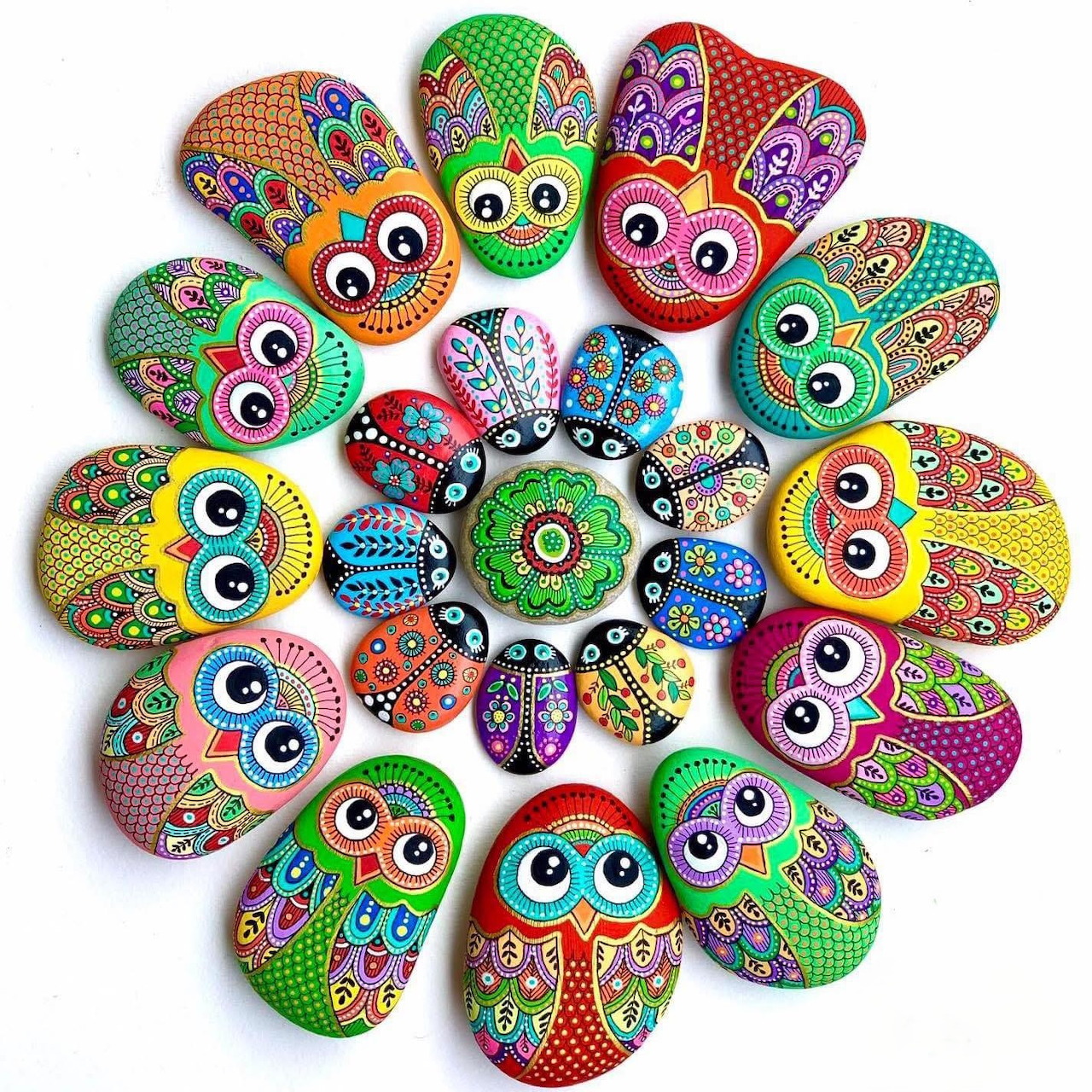 Circular mandala of painted rocks with owl and ladybug designs in bright colors and dot patterns