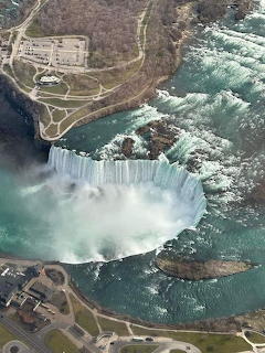 Aerial view of Niagara Falls with curved waterfall, mist, and turquoise river