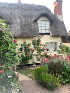 Thatched roof cottage with blooming garden flowers and stone path
