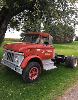 Vintage red Jefferson Rural fire department truck chassis on grass with trees behind