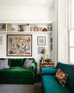 Bright living room with green velvet sofa, white built-in bookshelf, and teal chair