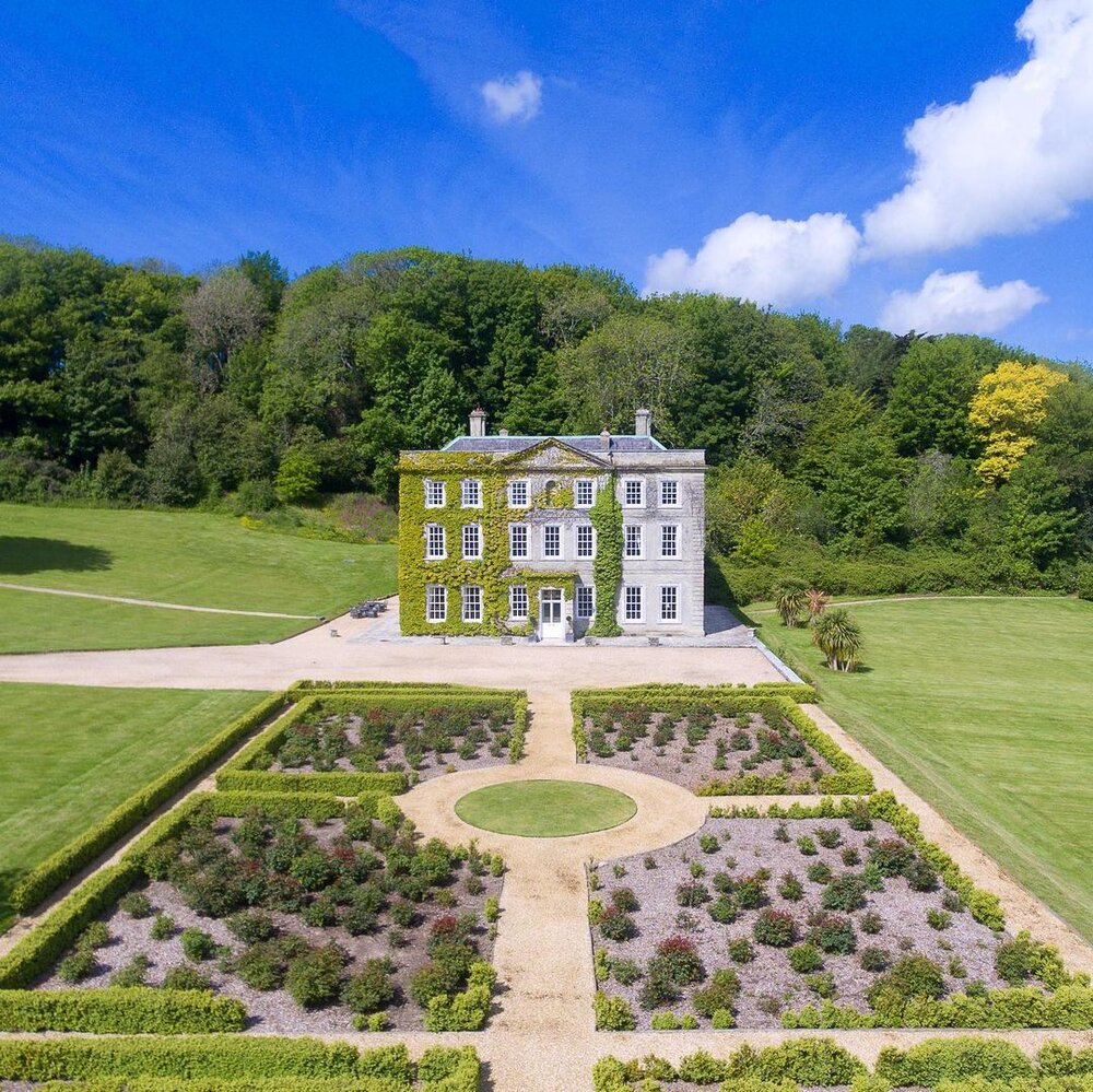 Aerial view of Georgian manor house with symmetrical formal gardens and tree-lined grounds