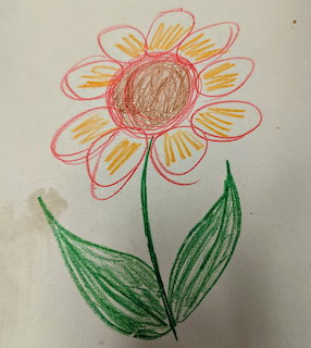 Child's crayon drawing of a colorful flower with pink petals and green leaves on paper