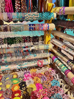 Rows of colorful beaded bracelets and bangles displayed at an outdoor flea market stall