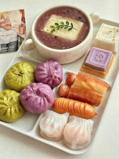 Assorted colorful Korean rice cakes and purple soup on white tray