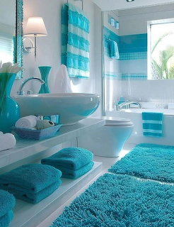 Modern bathroom with turquoise and white decor, glass sink, striped curtains, and fluffy towels