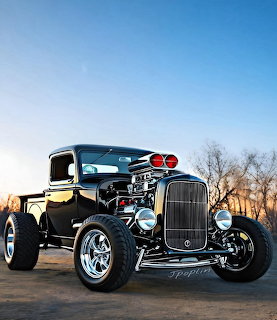 Black vintage hot rod pickup truck parked outdoors, viewed from the front