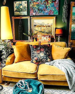 Mustard yellow velvet loveseat with floral pillows in a colorful eclectic living room with wall art