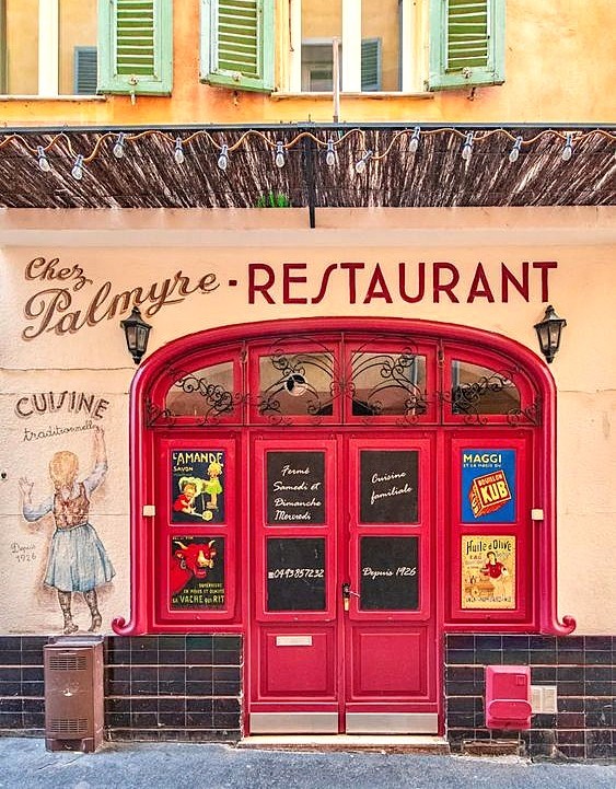 Red-doored French restaurant facade with Chez Palmyre sign and vintage chef figure