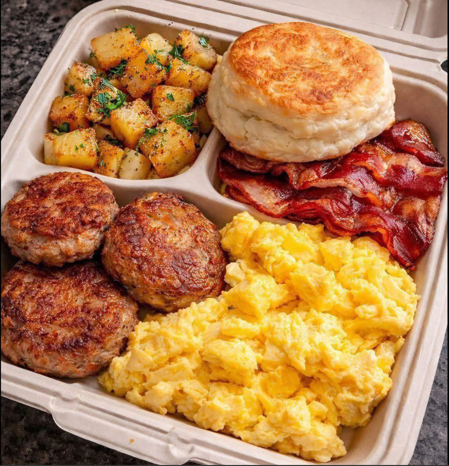 Takeout breakfast plate with eggs, bacon, sausage patties, biscuit, and home fries