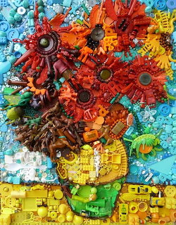 Mosaic vase with red flowers created from colorful plastic toys and blocks on blue background