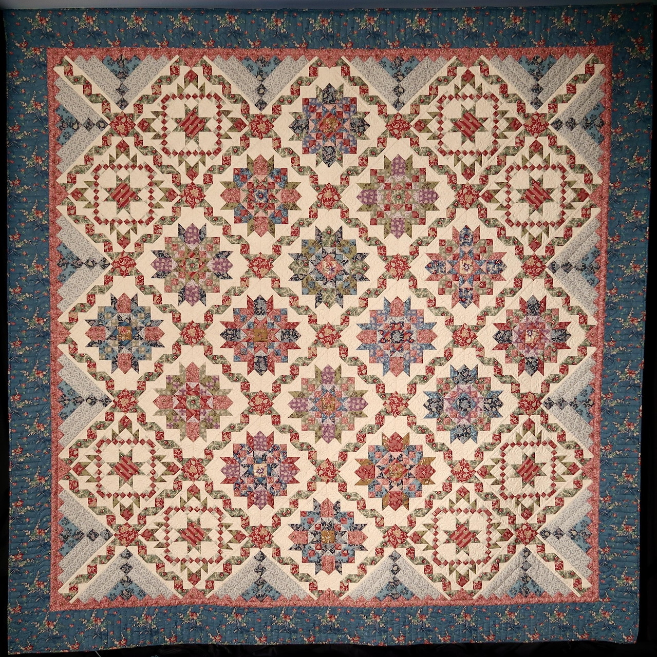 Traditional patchwork quilt with geometric star and floral medallions in cream, burgundy, and blue with ornate border