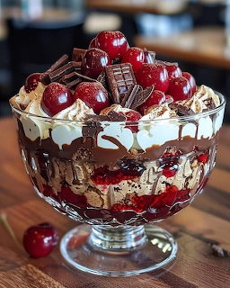 Layered cherry and chocolate trifle in a glass bowl on a wooden table
