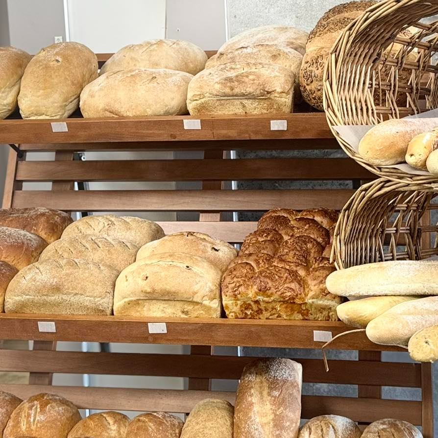 Loaves of bread and baguettes on wooden bakery shelves with wicker baskets