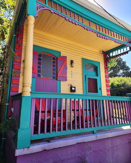 Colorful Victorian house with turquoise walls, yellow porch columns, and purple and pink trim details