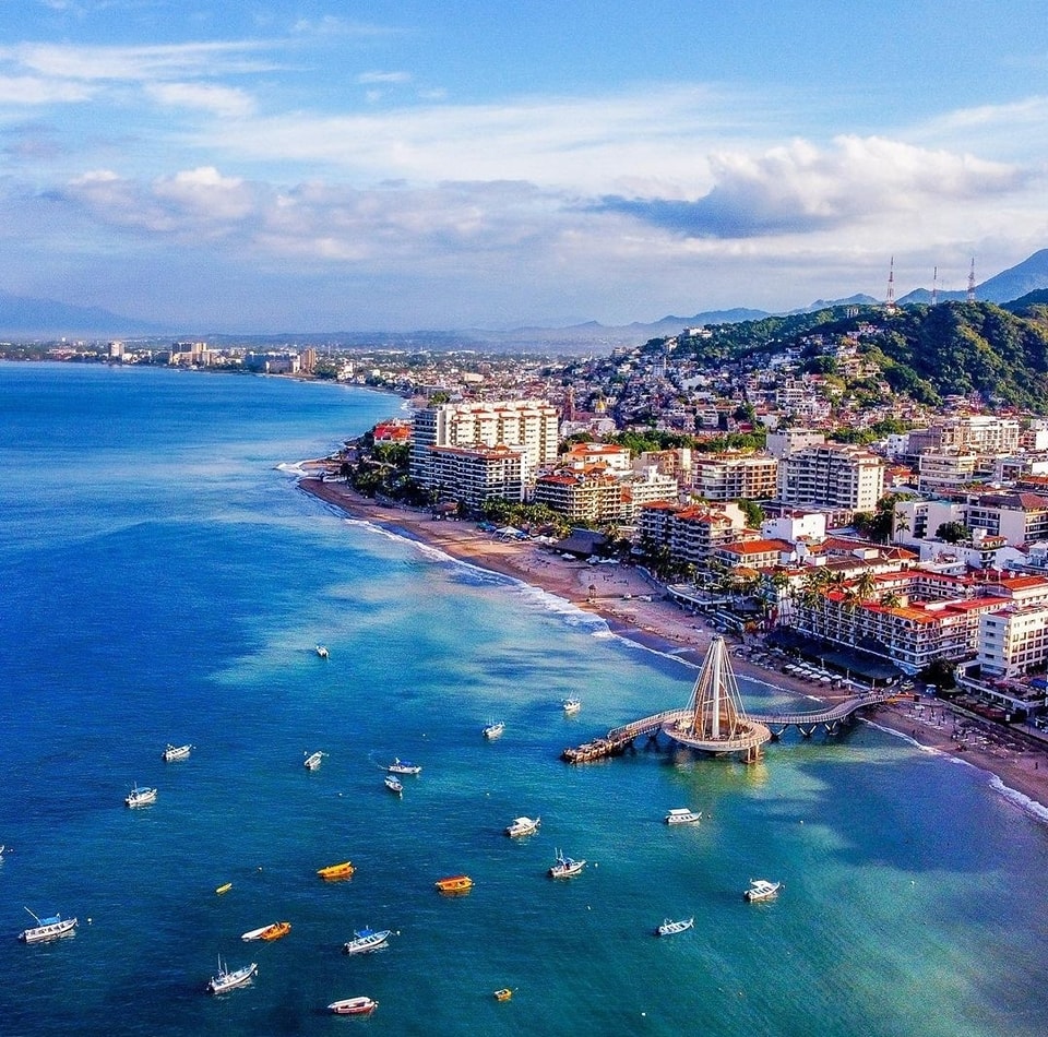 Aerial coastal view of Puerto Vallarta bay with boats, pier, beachfront hotels and hillside architecture