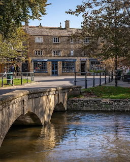 Stone bridge over a river in a village with old buildings and autumn trees
