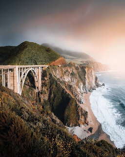 Concrete arch bridge on rugged Big Sur cliffs above a beach and ocean waves