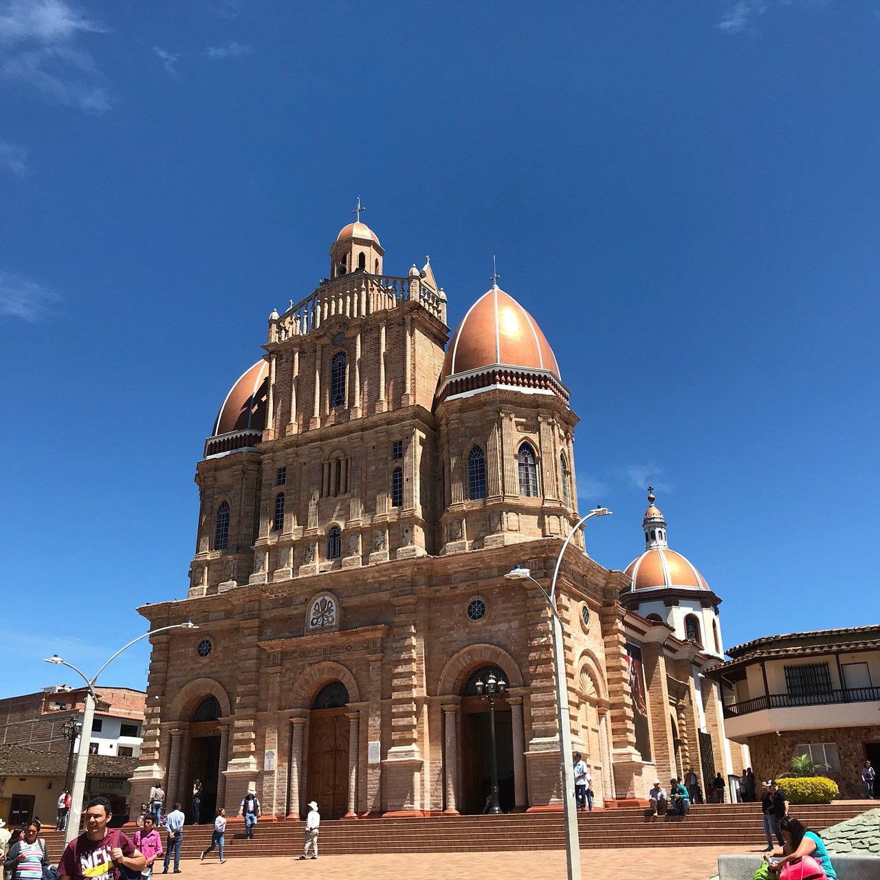 Brick church with copper domes in a town square beneath a bright blue sky