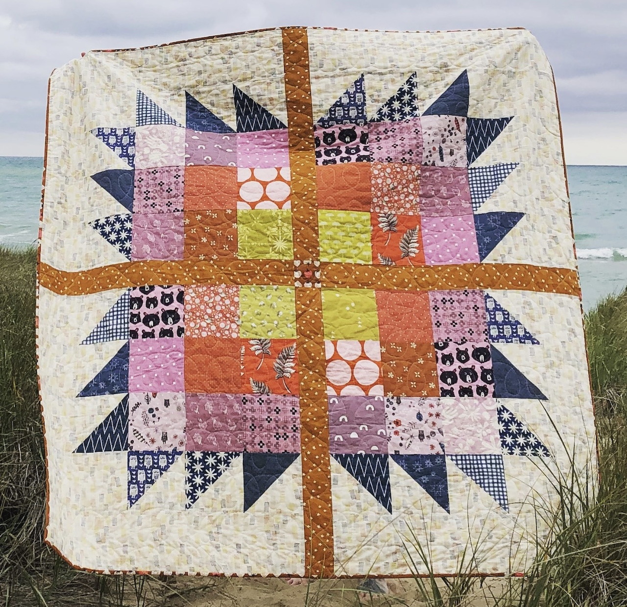Colorful patchwork quilt with star pattern hanging outdoors near beach