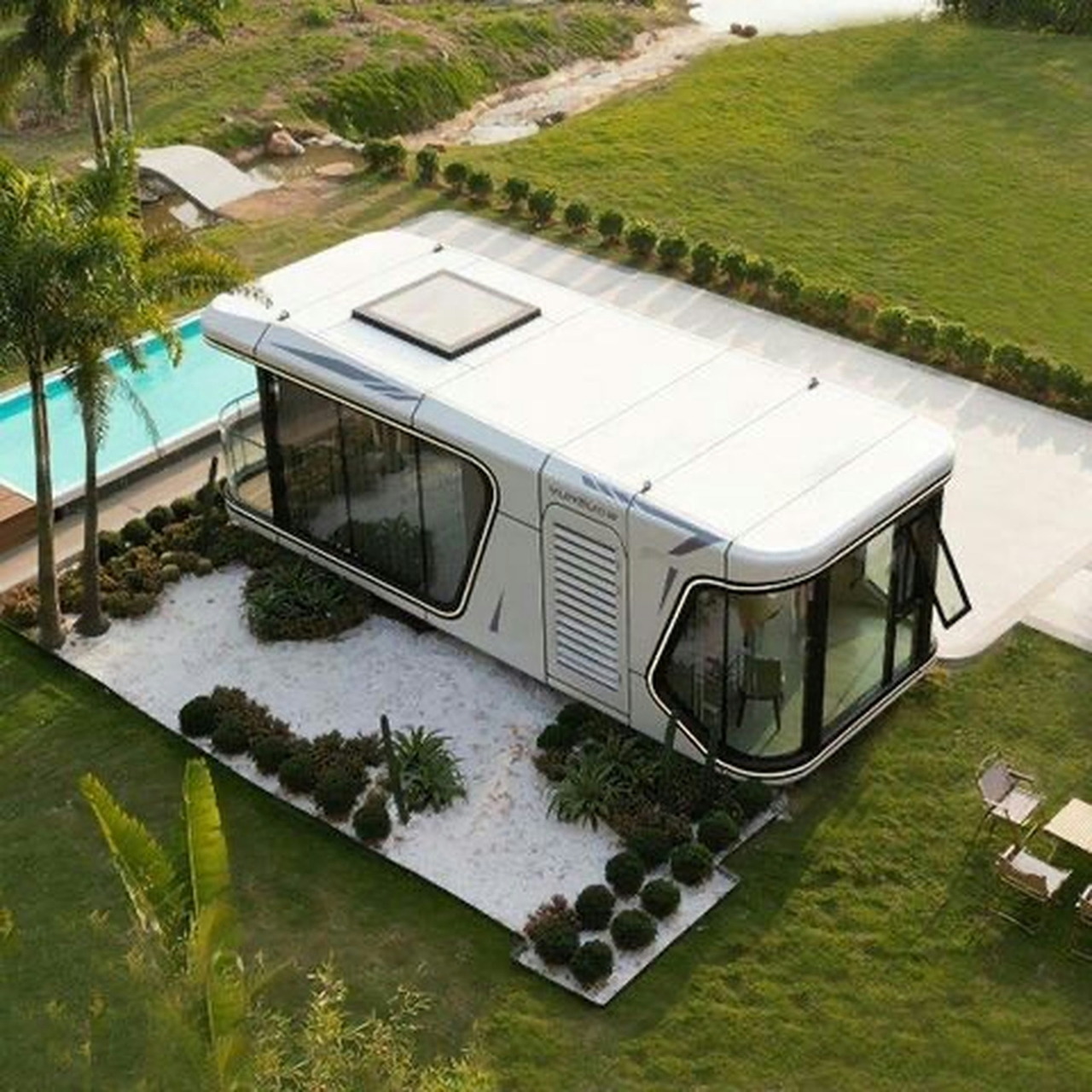 Aerial view of modern pool house with curved roof beside turquoise pool in tropical garden