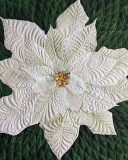 White quilted poinsettia flower with ornate stitching on green quilted background