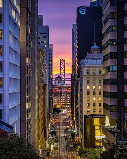 Golden Gate Bridge framed by San Francisco buildings at sunset with purple sky