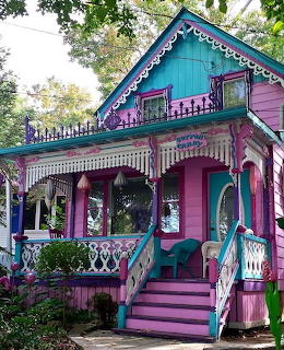 Colorful Victorian cottage with turquoise and pink siding, white decorative trim, front porch and steps