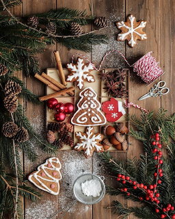 Christmas gingerbread cookies with festive ornaments and pine branches on wooden table