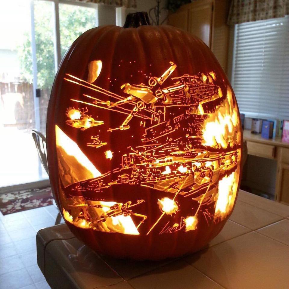 Carved pumpkin with glowing Star Wars X-Wing fighter design on kitchen counter
