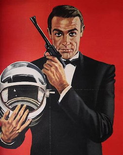 Man in tuxedo holding gun and space helmet on red background