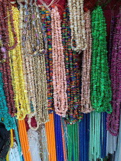 Multiple colorful bead and chipped stone necklaces hanging on a display rack