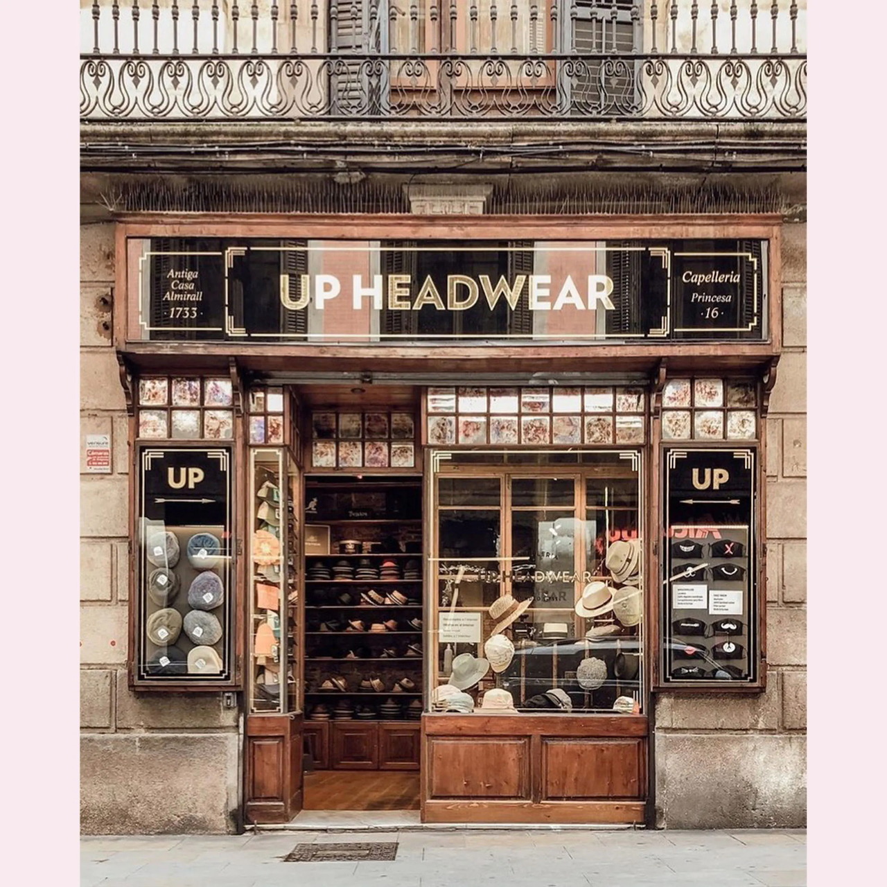 Ornate vintage storefront of UP Headwear shop with wooden doors and display windows in classic European building