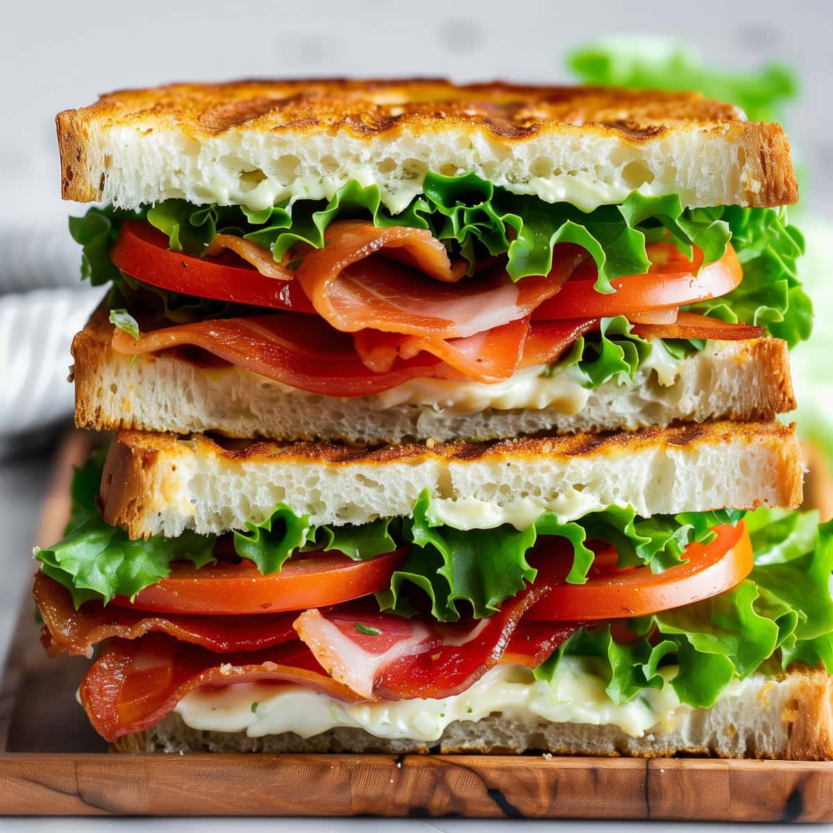 Two stacked BLT sandwiches with bacon, lettuce, and tomato on toasted bread