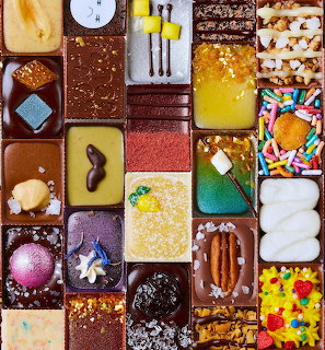Overhead view of assorted chocolate and candy dessert squares arranged in a colorful grid pattern
