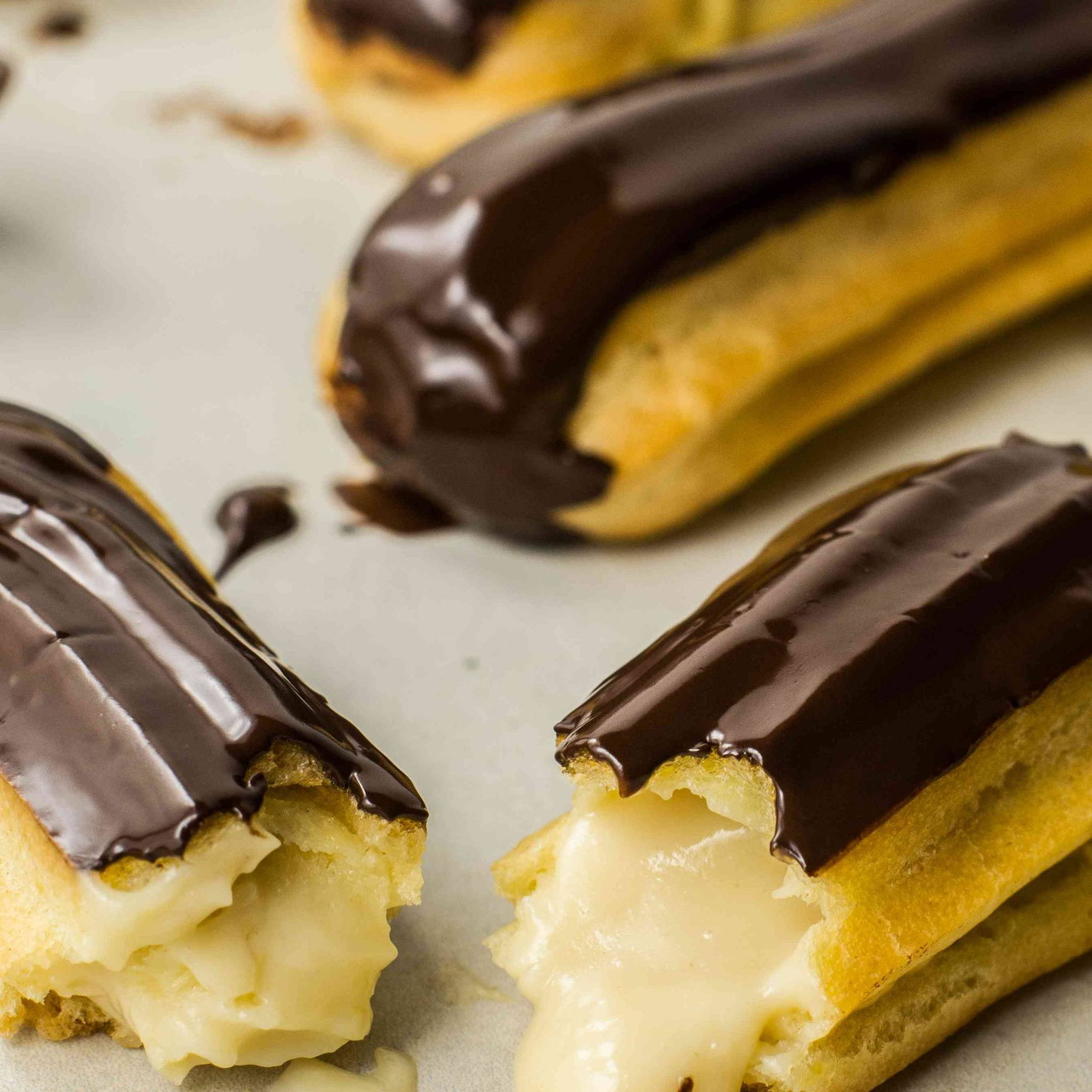 Chocolate eclairs with custard filling on white surface