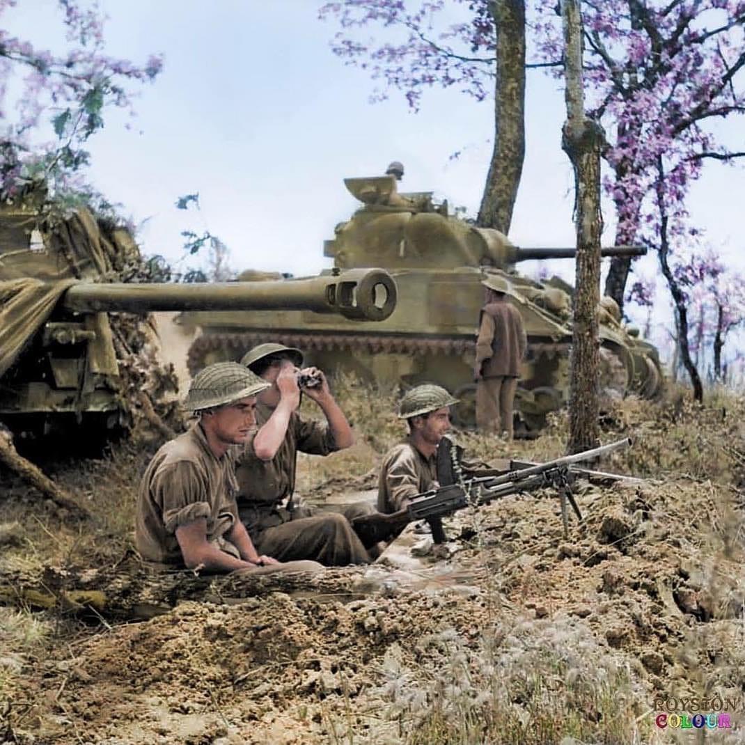 Three soldiers in a trench beside a tank in a dry outdoor wartime scene