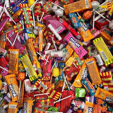 Dense pile of colorful wrapped candies, chocolates, and lollipops